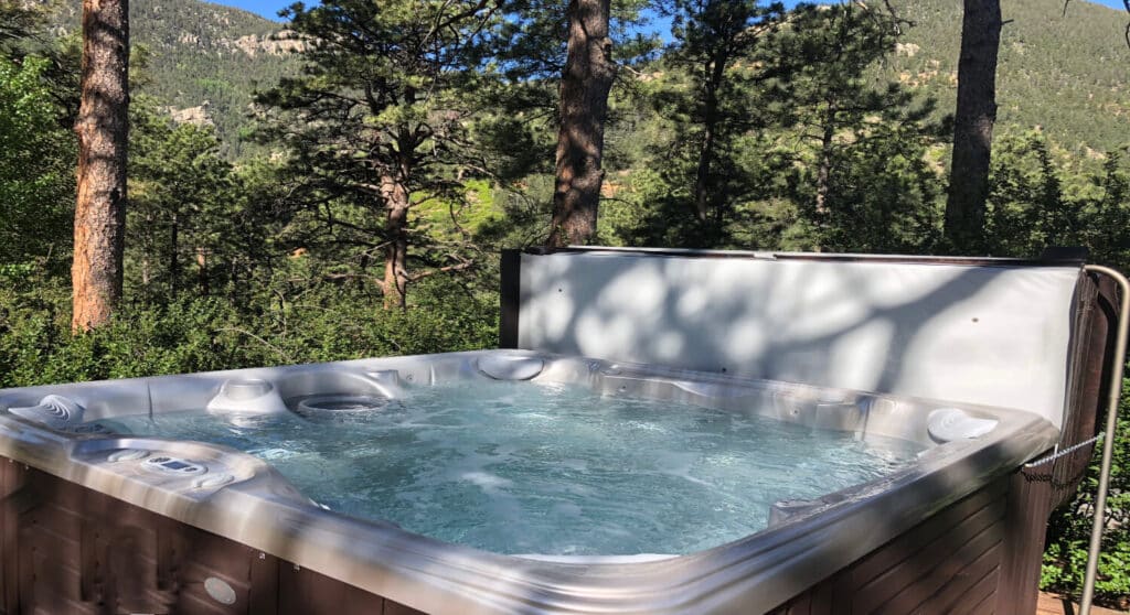 close up of a hot tub with bubbling water in the midst of pine trees and mountains in the background